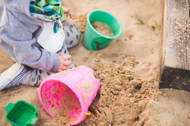 little boy digging for dinosaur egg in sand pit